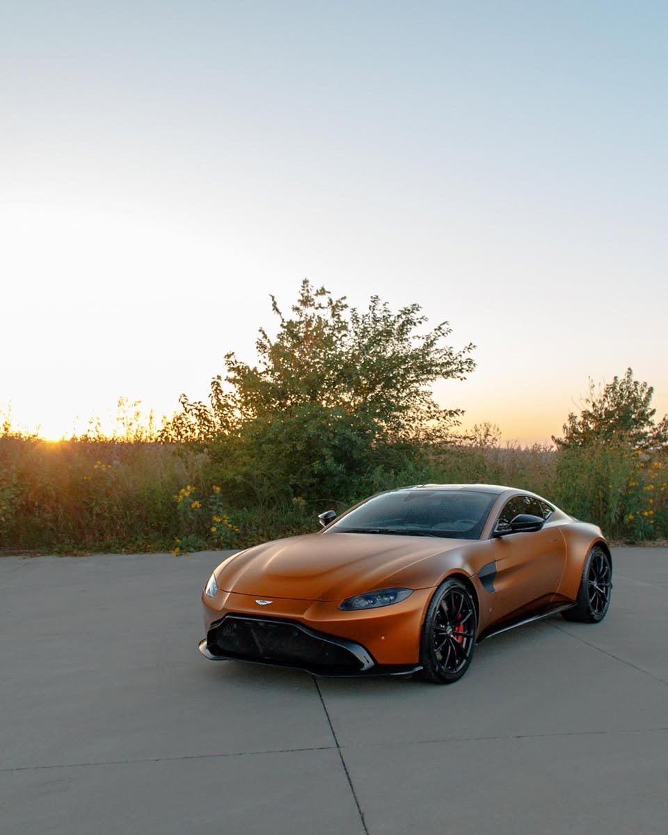 Matte orange Aston Martin Vantage front three-quarter at sunset after an exterior detail in Altoona