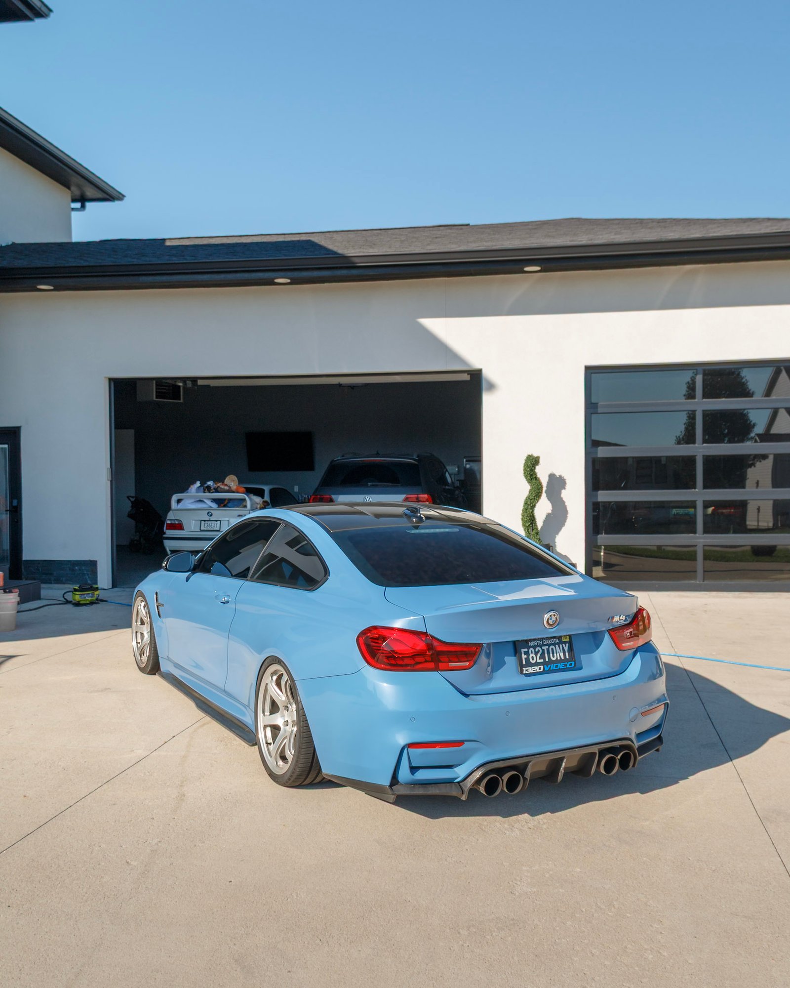 Rear three-quarter of the light blue BMW M4 on the driveway