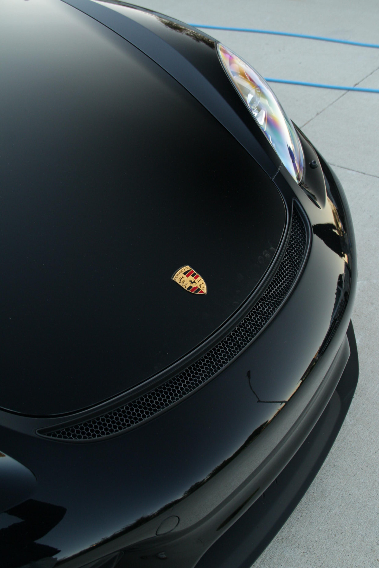 Porsche crest on the hood of a black 718 Spyder after the exterior detail