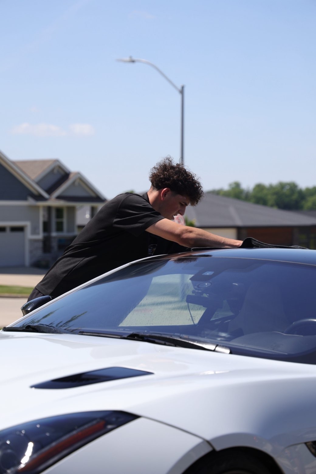 Jake, owner of Street Standard Detailing, hand-drying a Chevrolet Corvette C8 in Des Moines