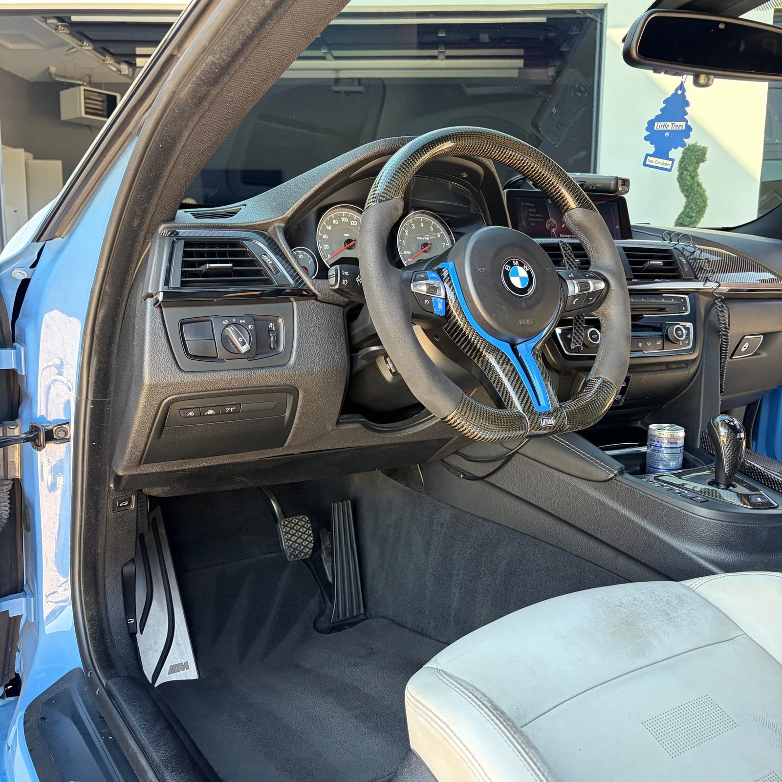 BMW M4 driver footwell and carbon steering wheel with the door open