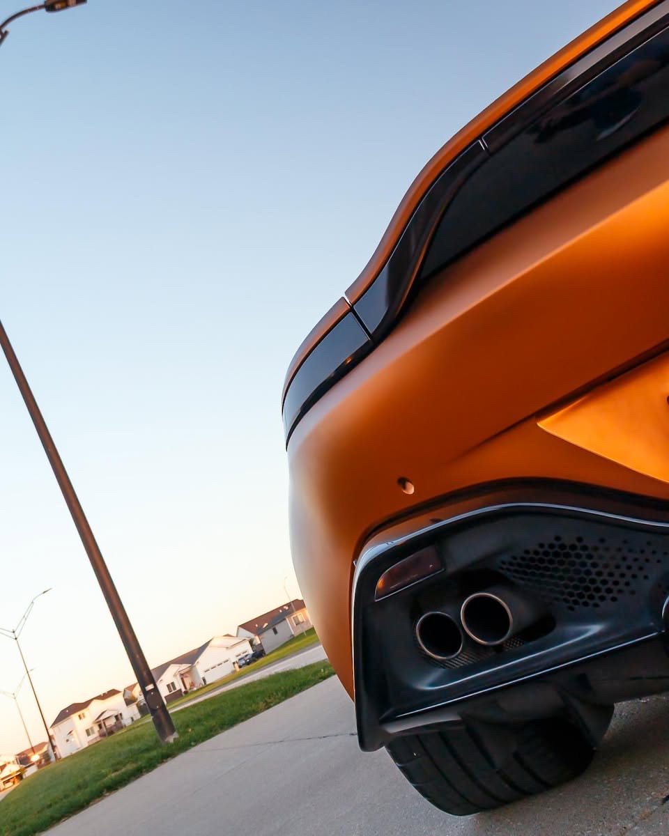 Matte orange Aston Martin Vantage rear bumper and quad exhaust tips after an exterior detail in Altoona