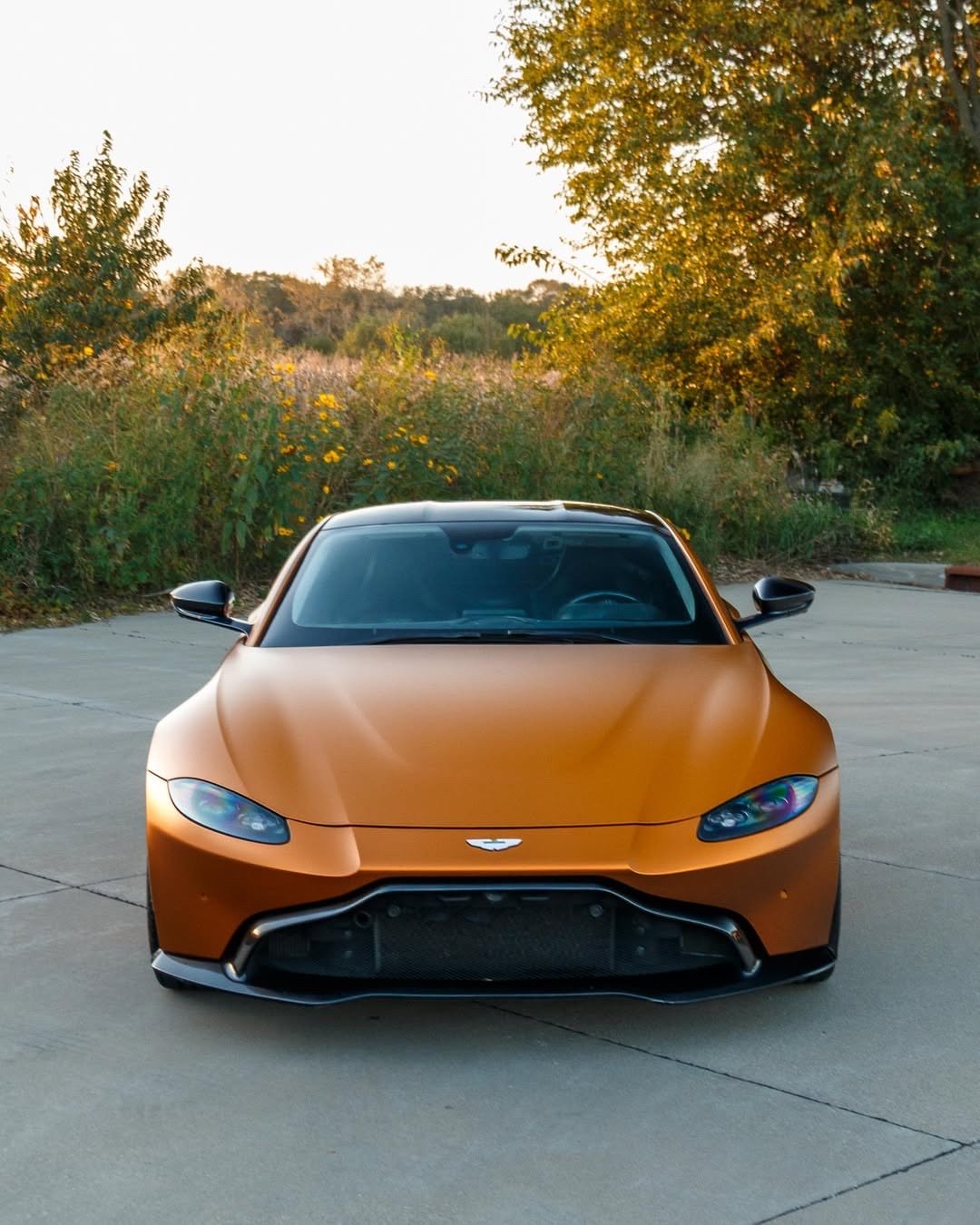 Matte orange Aston Martin Vantage front view on a concrete pad after an exterior detail in Altoona