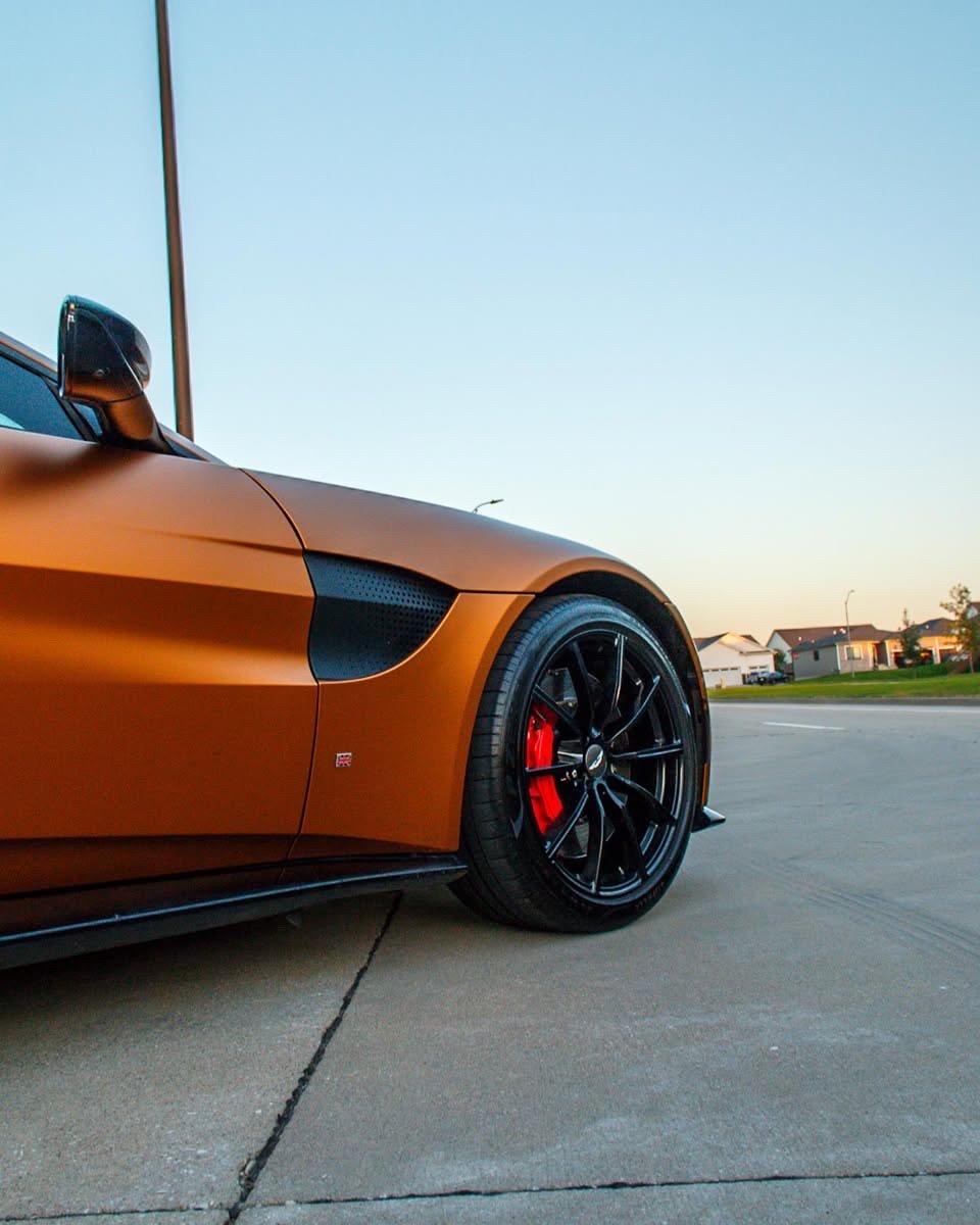 Matte orange Aston Martin Vantage front wheel and red brake caliper after an exterior detail in Altoona