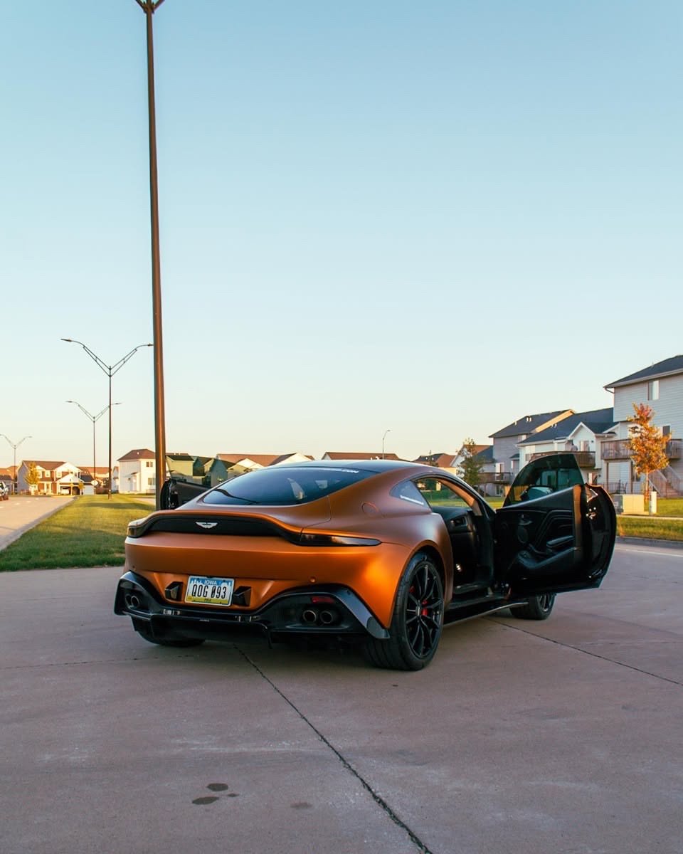 Matte orange Aston Martin Vantage rear three-quarter with driver door open after an exterior detail in Altoona