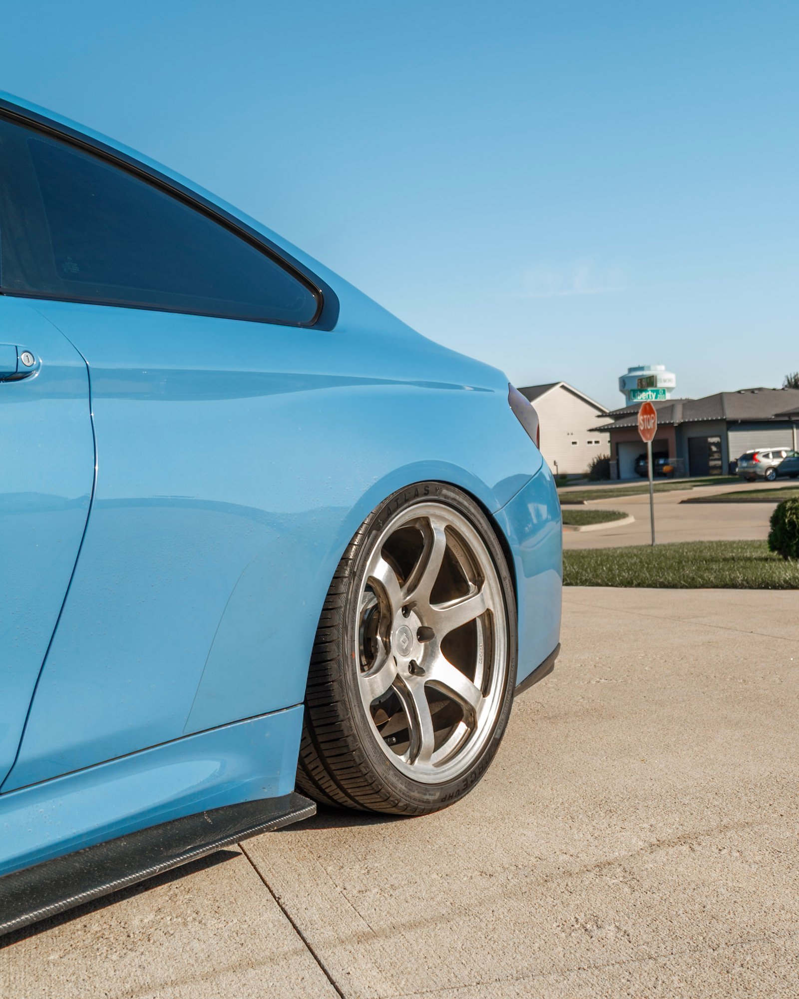 Light blue BMW M4 rear and side profile in front of the garage