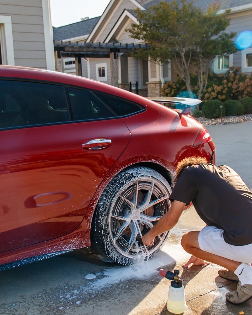 Jake scrubbing the red Mercedes-AMG GT 63 S rear wheel during the wash