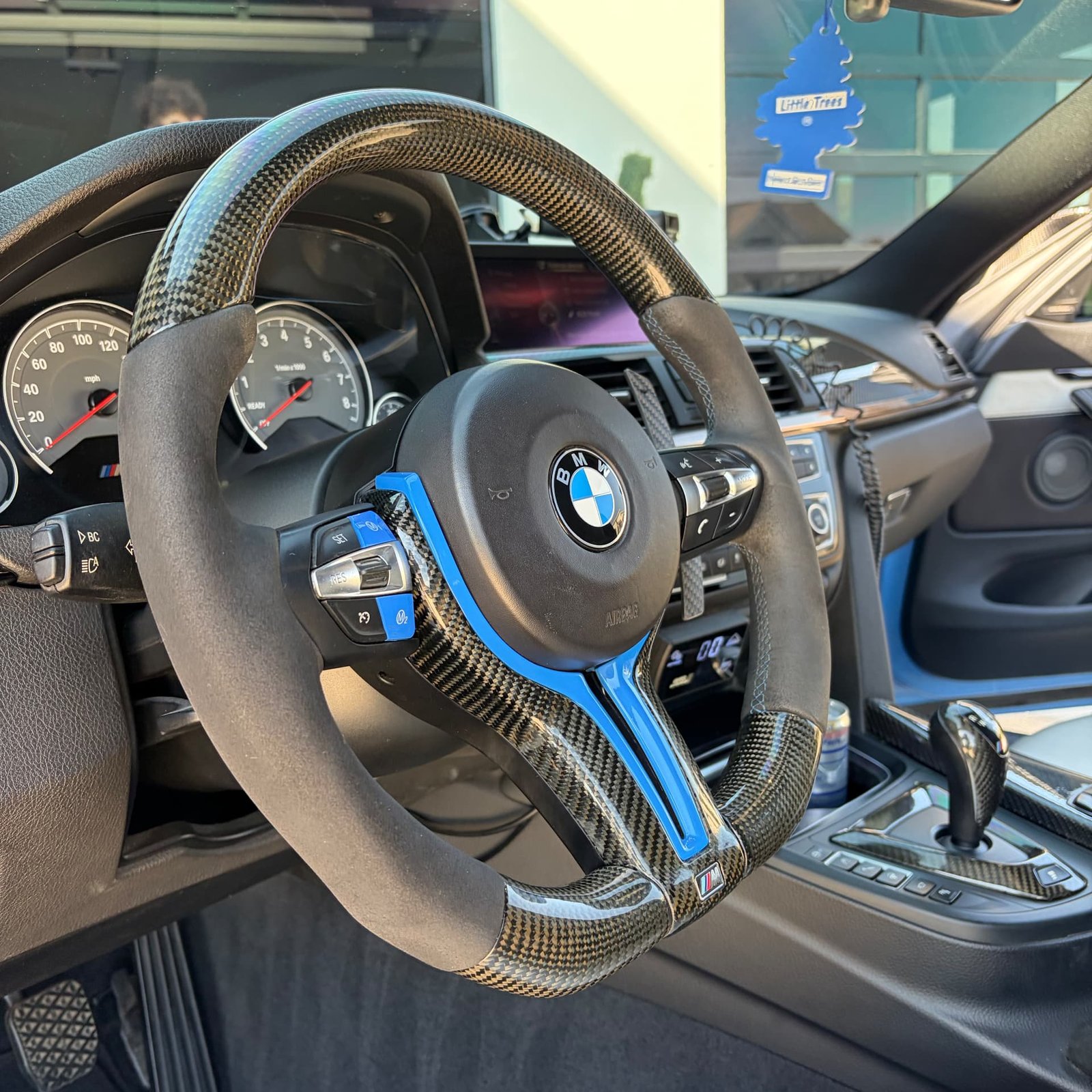 Close-up of the BMW M4 carbon fiber steering wheel with blue accents
