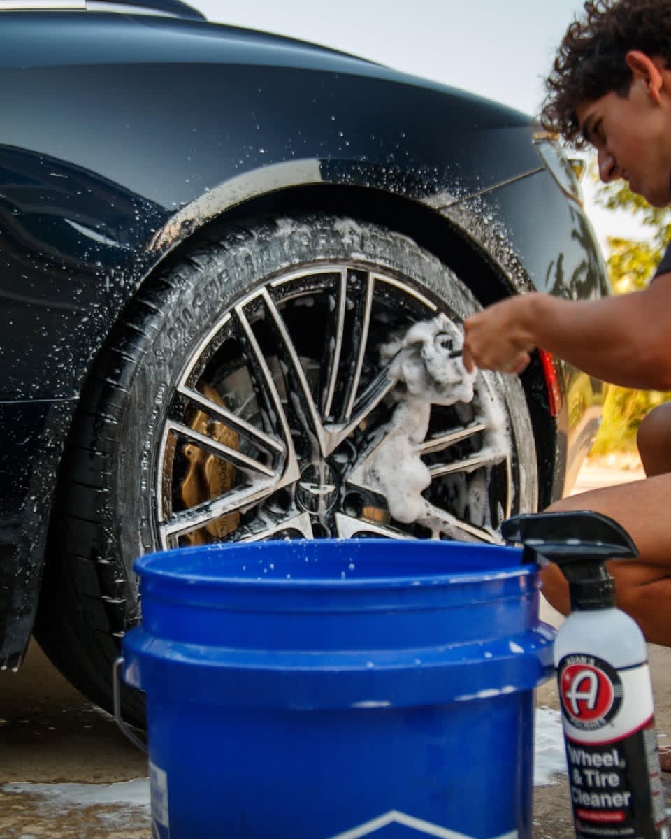 Jake, owner of Street Standard Detailing, carefully cleaning an Aston Martin wheel
