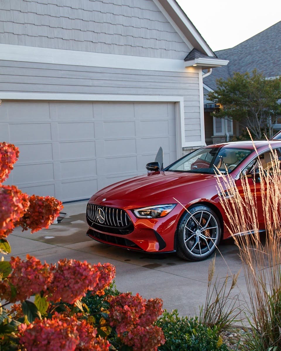 Red Mercedes-AMG GT 63 S front quarter framed by autumn plants in the driveway