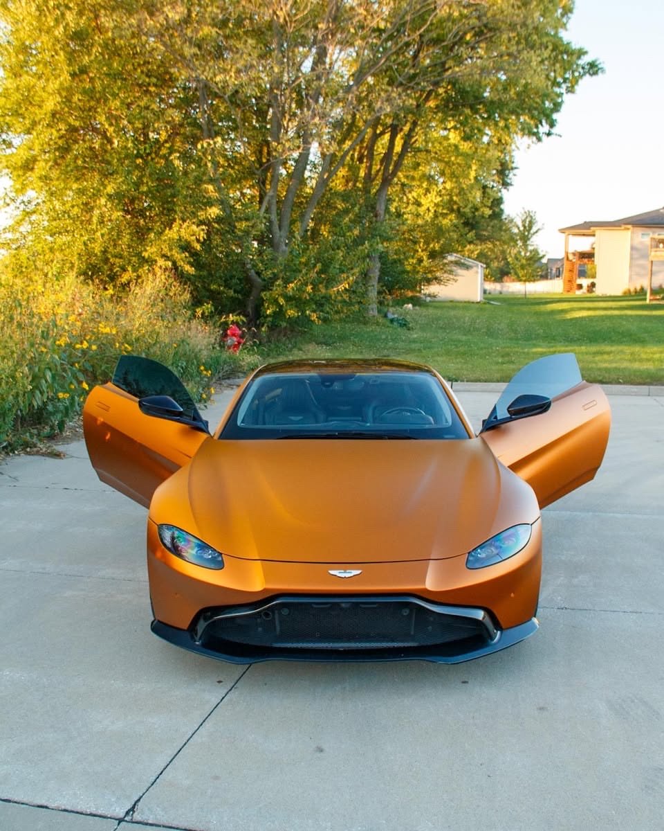 Matte orange Aston Martin Vantage with both doors open, front view after an exterior detail in Altoona