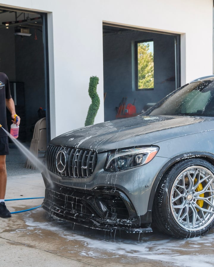 Grey Mercedes-AMG being rinsed in front of a garage, photographed by Kenny