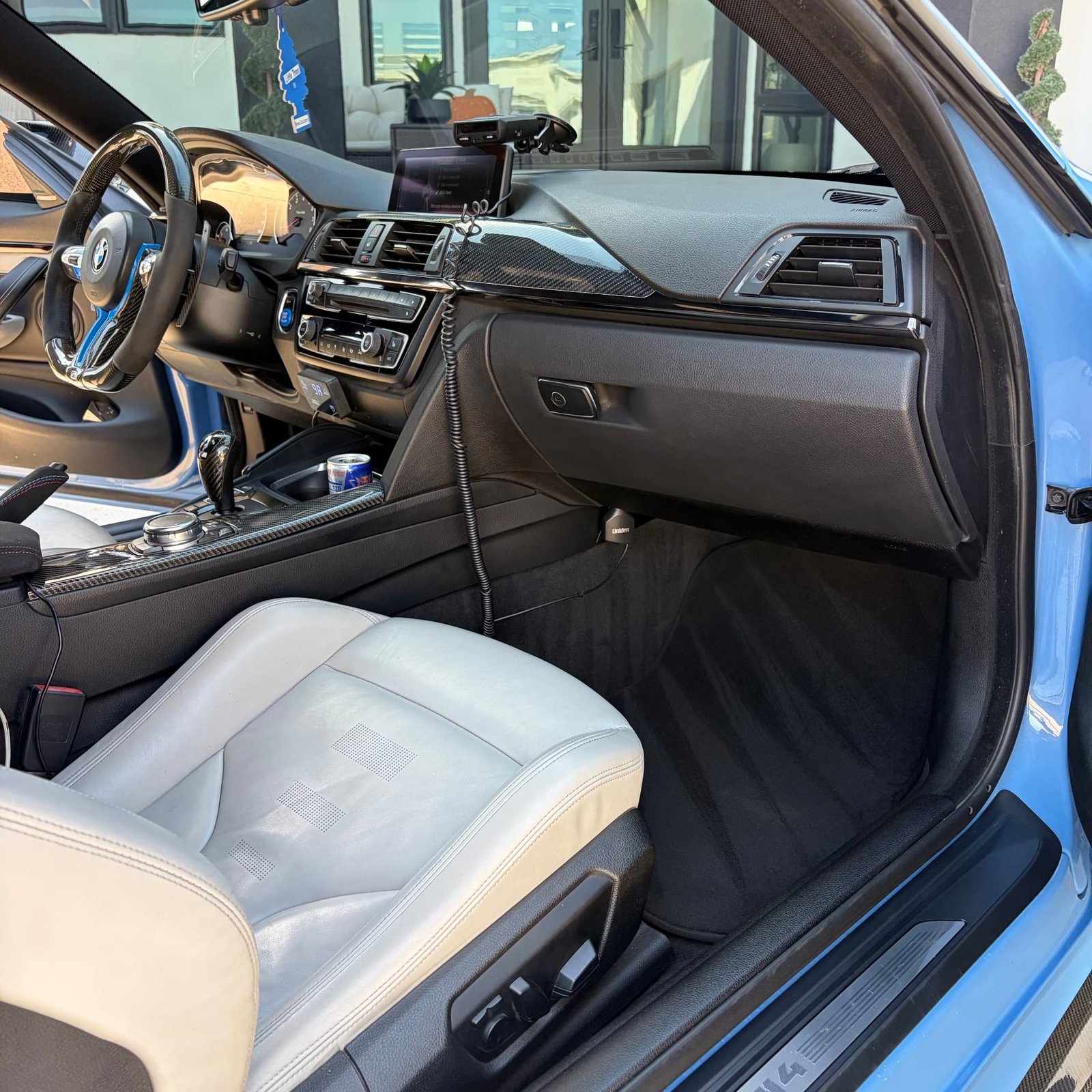 White leather passenger seat and dash of the BMW M4 with the garage door behind